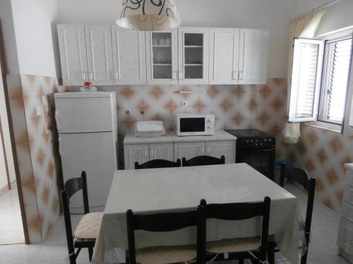 uma cozinha com uma mesa com cadeiras e um frigorífico em Apartments by the sea Sevid, Trogir - 15742 em Sevid
