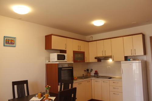 kuchnia z białymi szafkami, stołem i lodówką w obiekcie Apartments with a parking space Split - 15964 w Splicie
