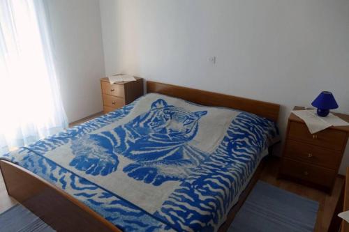 ein Bett mit einer blauen Decke mit einem Tiger drauf in der Unterkunft Apartment Supetarska Draga - Donja 15983c in Rab