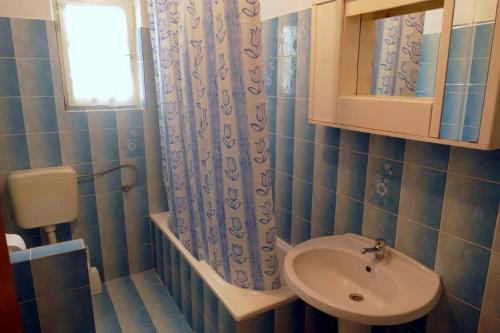 a blue tiled bathroom with a sink and a mirror at Apartment Supetarska Draga - Donja 15983c in Rab