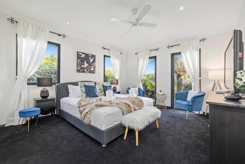 a bedroom with a bed and blue chairs and windows at Sandstone Estate in Red Hill