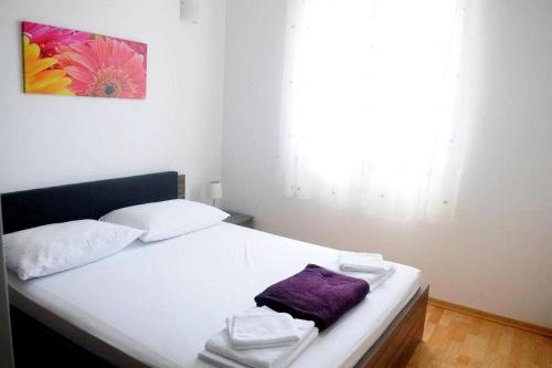 sypialnia z białym łóżkiem z fioletowym ręcznikiem w obiekcie Apartments with a parking space Klenovica, Novi Vinodolski - 15987 w mieście Klenovica