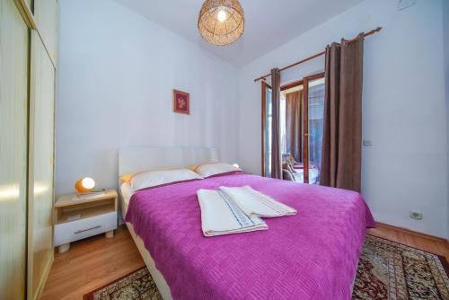 a bedroom with a purple bed with towels on it at Apartments by the sea Sobra, Mljet - 15993 in Babino Polje