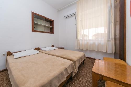 two beds in a room with a table and a window at Triple Room Gradac 16006c in Gradac