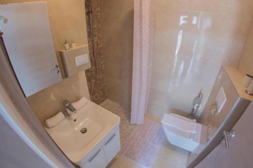 a white bathroom with a sink and a toilet at Apartments by the sea Gradac, Makarska - 16039 in Gradac