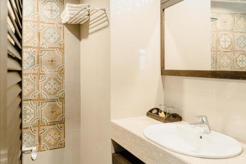 uma casa de banho com um lavatório e um espelho em Palm Beach Hotel Bali em Kuta