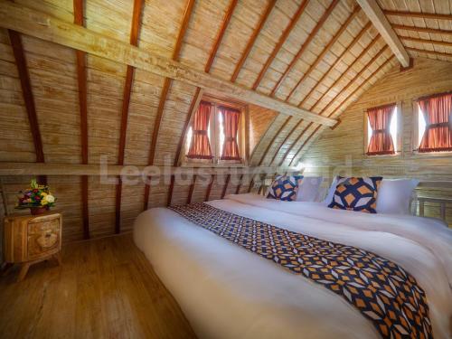 ウルワツにあるWisnu Lumbung Uluwatuの木製の部屋にベッド1台が備わるベッドルーム1室があります。