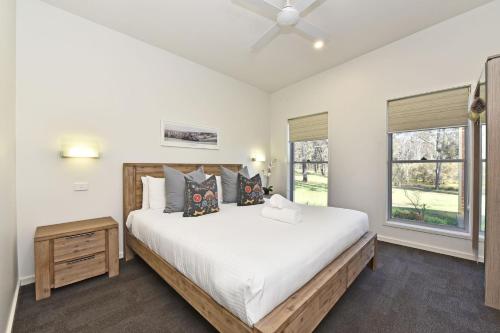 ein Schlafzimmer mit einem großen weißen Bett und einem Fenster in der Unterkunft Ironbark Hill Villa 1 Tyrian in Pokolbin