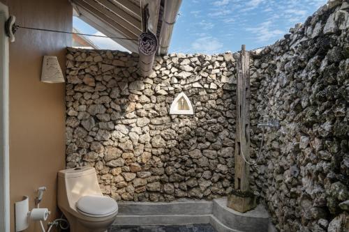 ein Badezimmer mit einer Steinmauer und einem WC in der Unterkunft The Chillhouse Canggu by BVR Bali Holiday Rentals in Canggu