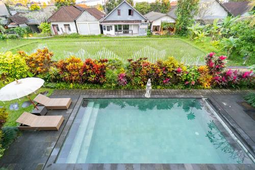 a swimming pool with two chairs and an umbrella at The Dayuh Ubud in Ubud