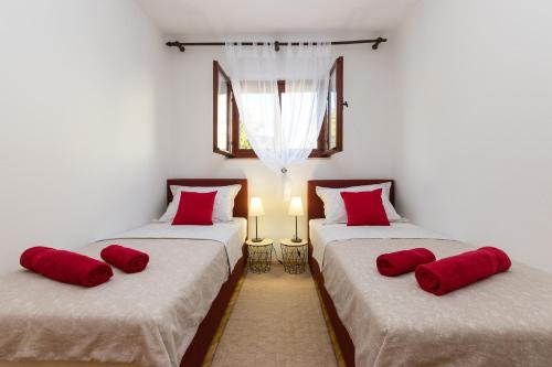 two beds in a room with red pillows on them at Apartments with parking space Kastel Stafilic, Kastela - 16086 in Kaštela