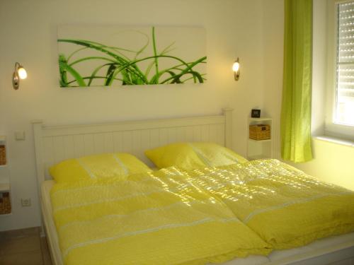- un lit avec une couette jaune dans une chambre dans l'établissement Grachtenstube, à Greetsiel
