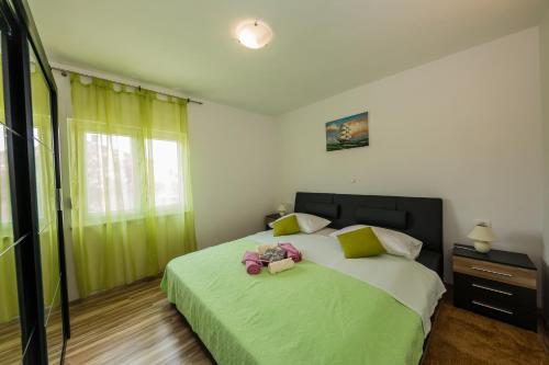 Un dormitorio con una cama verde con un osito de peluche. en Apartments with a parking space Kastel Stari, Kastela - 16087, en Kaštela