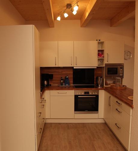 a kitchen with white cabinets and black appliances at Aloha in Greetsiel
