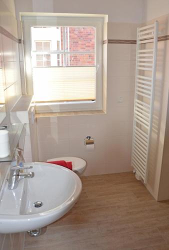 a white bathroom with a sink and a window at Aloha in Greetsiel