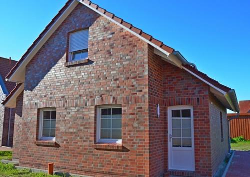a brick house with a white door and windows at Aloha in Greetsiel