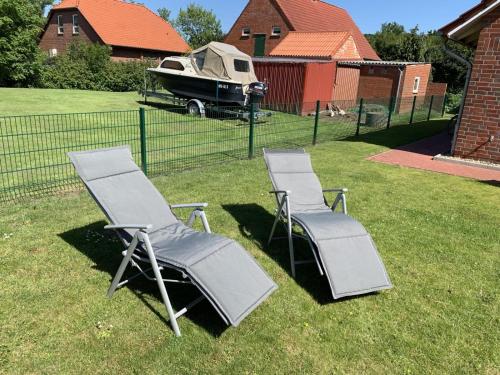 two lawn chairs and a boat in a yard at Aloha in Greetsiel