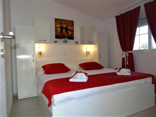 ein Schlafzimmer mit einem großen weißen Bett mit roten Kissen in der Unterkunft Apartment Pag 16100c in Pag