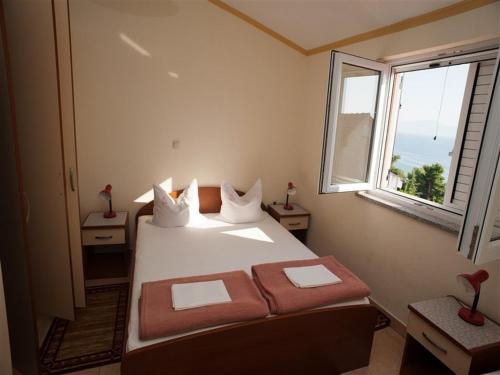 1 dormitorio con 1 cama y ventana grande en Apartments and rooms by the sea Podaca, Makarska - 16114, en Podaca