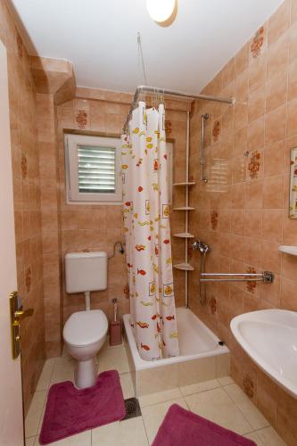 a bathroom with a toilet and a tub and a shower curtain at Apartments and rooms by the sea Podaca, Makarska - 16114 in Podaca
