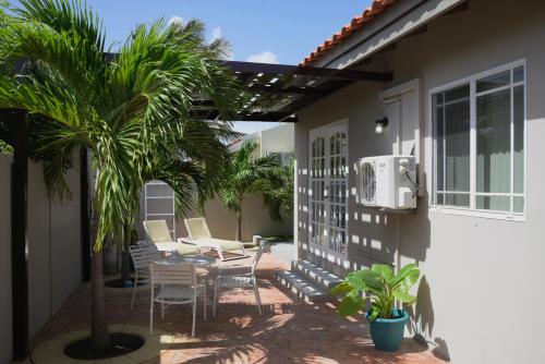 een patio met stoelen en een palmboom naast een huis bij Beach Homes Aruba in Noord