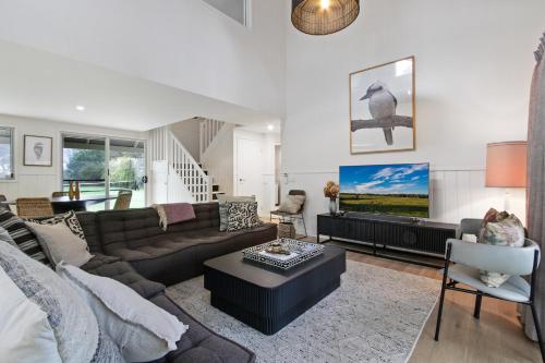 a living room with a couch and a tv at Cliff House Cottage - Modern Metung Retreat in Metung