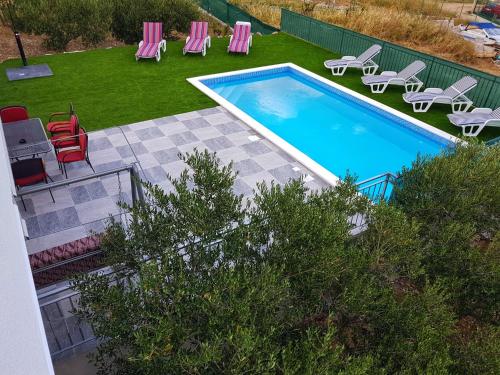 an overhead view of a swimming pool with chairs and a yard at Family friendly house with a swimming pool Kastel Novi, Kastela - 16199 in Kastel Novi