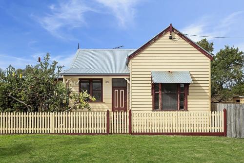 a small house with a fence in a yard at Fishermans Cottage in Queenscliff