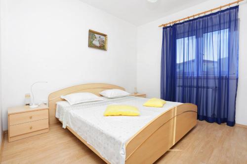 a bedroom with a bed with yellow pillows on it at Apartments by the sea Rogoznica - 16216 in Rogoznica