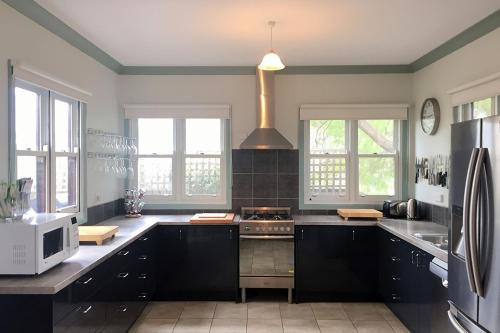 a kitchen with black cabinets and a stove top oven at By The Bay in Queenscliff