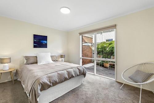 a bedroom with a bed and a sliding glass door at Bay Bright in Point Lonsdale
