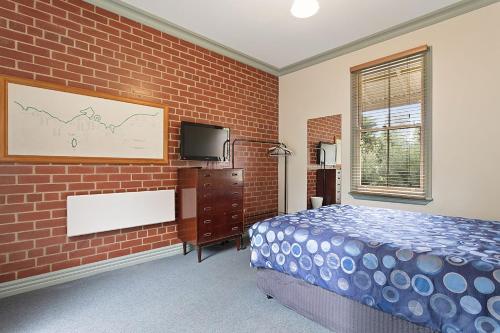 a bedroom with a bed and a brick wall at Large House on Wharf Street in Queenscliff