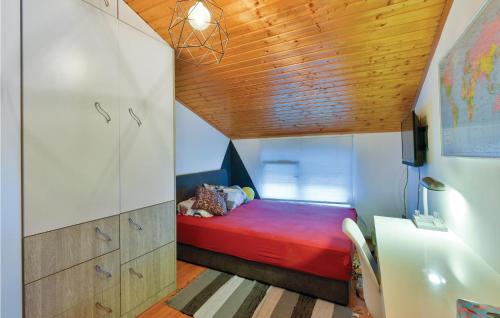 Habitación pequeña con cama roja y techo de madera. en Cozy Home In Krizevci With House A Panoramic View, en Križevci