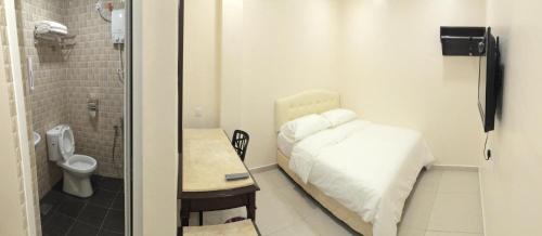 een kleine badkamer met een bed en een toilet bij Sam Hotel in Sitiawan