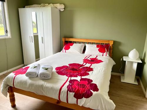 ein Schlafzimmer mit einem Bett mit roten Blumen darauf in der Unterkunft Brett's Rest Nel in Kingscote
