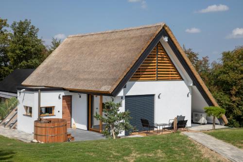 a white cottage with a thatched roof at Hiska B&N Podlehnik in Podlehnik
