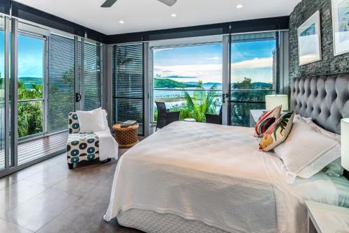um quarto com uma cama grande e janelas grandes em Habitat on Hamilton Island by HIHA em Hamilton Island