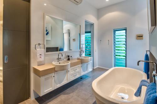 a bathroom with two sinks and a large mirror at Habitat on Hamilton Island by HIHA in Hamilton Island