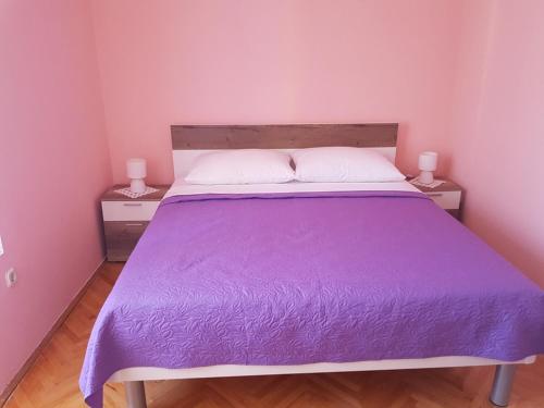 ein Bett mit einer lila Bettdecke in einem Schlafzimmer in der Unterkunft Apartments with a parking space Vodice - 16060 in Vodice