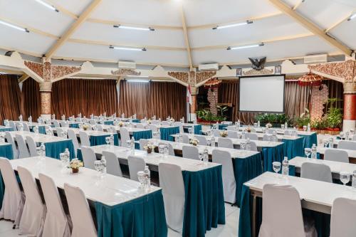 a conference hall with white tables and chairs and a screen at Palm Beach Hotel Bali in Kuta