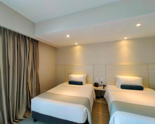 a hotel room with two beds and a window at Solea Mactan Resort in Mactan