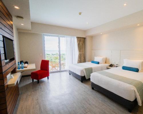 a hotel room with two beds and a red chair at Solea Mactan Resort in Mactan
