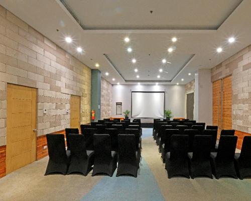 a conference room with black chairs and a projection screen at Solea Mactan Resort in Mactan