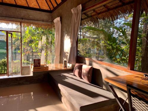 a room with a couch and a table and windows at khaokho keree tara in Khao Kho