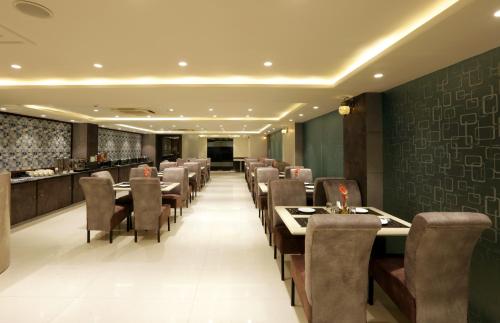 a restaurant with tables and chairs and a bar at Hotel Sakura by Maps in Gurgaon