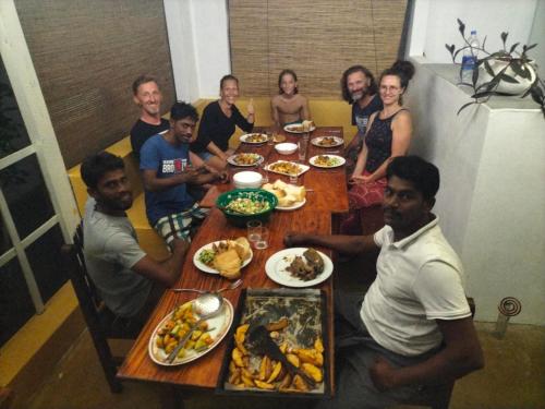 um grupo de pessoas sentadas à volta de uma mesa com comida em Another World em Arugam Bay