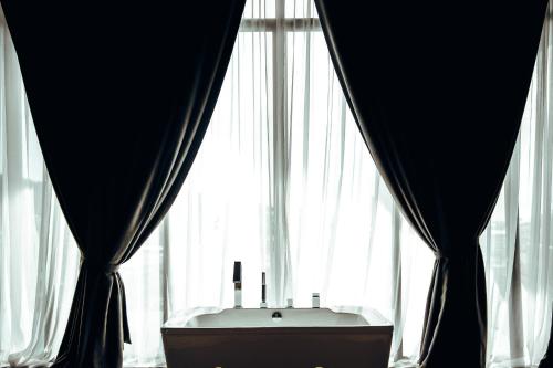 a bath tub in front of a window with curtains at The Senses Resort & Pool Villas, PHUKET in Patong Beach