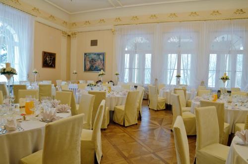 uma sala cheia de mesas e cadeiras com toalha de mesa branca em Zespół Pałacowo-Parkowy w Ostromecku em Ostromecko