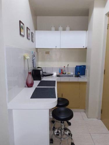 a white kitchen with two stools at a counter at Budget Friendly Condo for Rent in Valley Mansions in Cainta