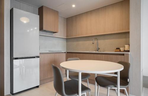 a kitchen with a table and chairs and a refrigerator at Geoje Mongdol Beach H Avenue Hotel in Geoje 